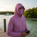 Person wearing pink hoodie and neck gaiter with Florida fishing background